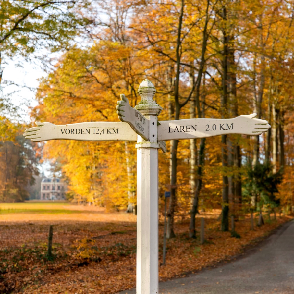 Wit authentiek straatbordje met de richting voor Laren, Vorden