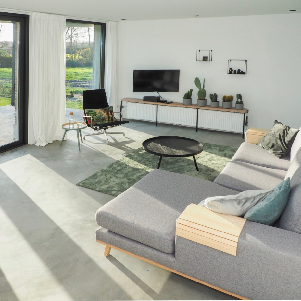 Grijze bank, groen kleed en grote ramen in een vakantiehuis