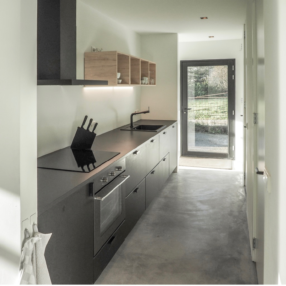 Zwarte keuken met betonnen vloer in een vakantiehuis