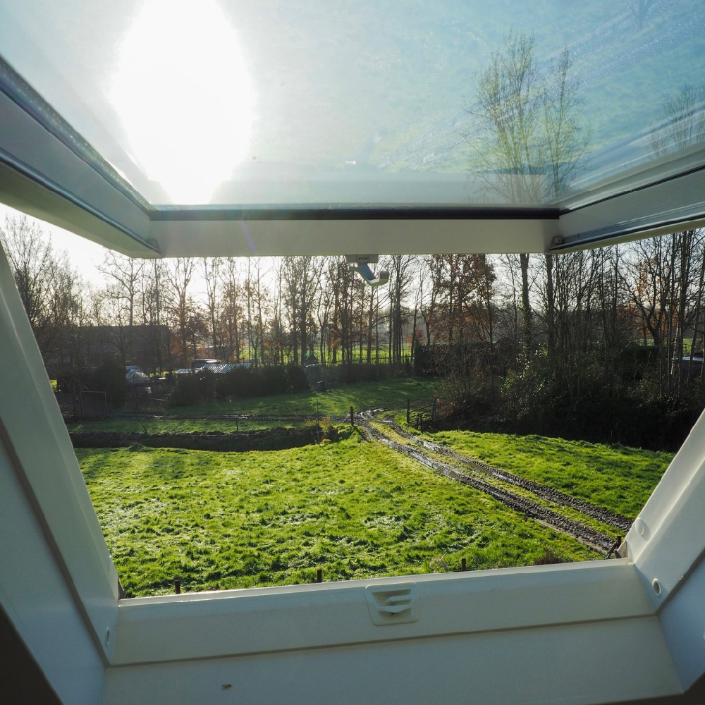 Uitzicht vanuit een dakraam over de tuin van een vakantiehuisje
