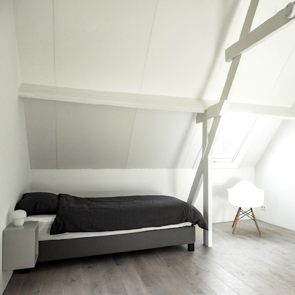 Witte slaapkamer met zwart bed in een vakantiehuisje