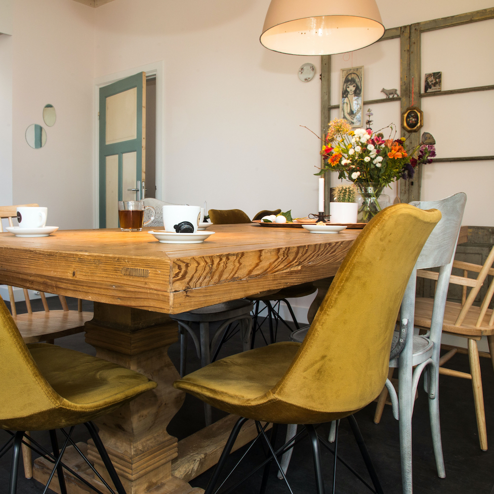 Eetkamer met verschillende stoelen rond de tafel