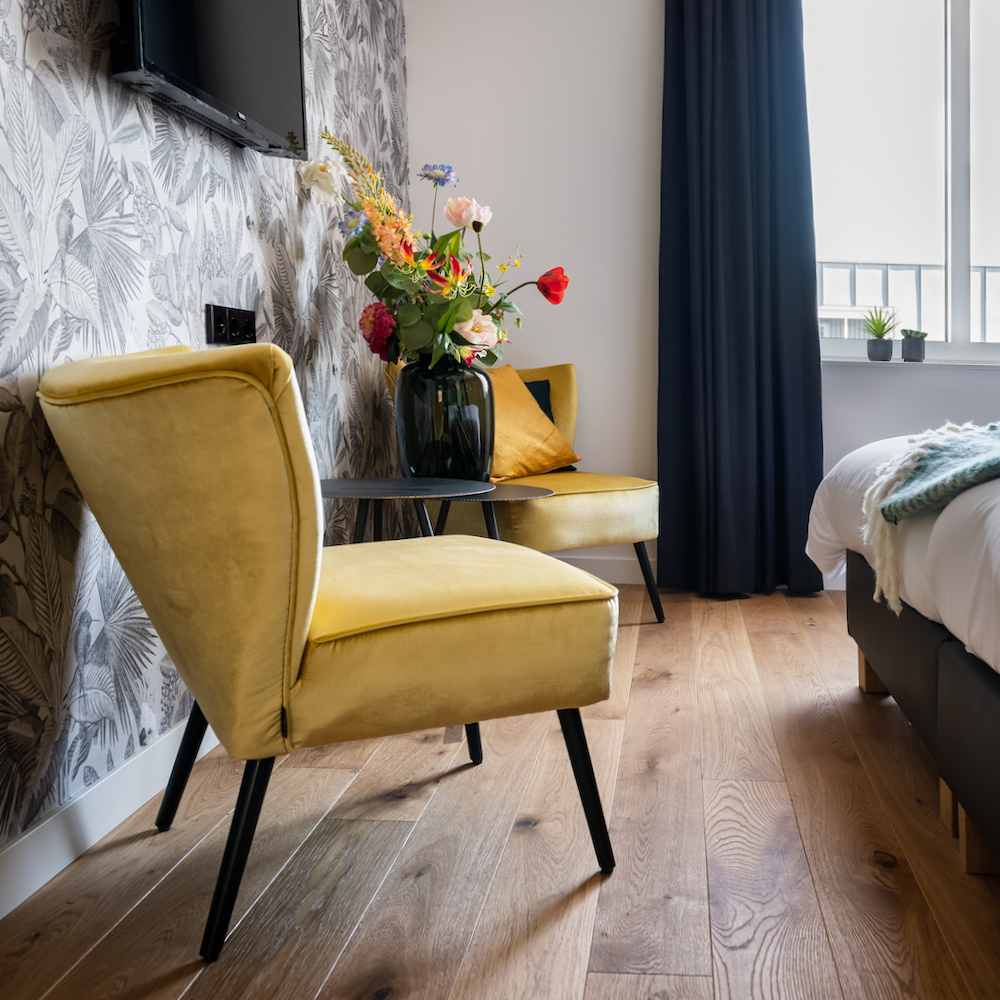 Gele fauteuils met bos bloemen op hotelkamer in Hotel de Beerze in Brabant