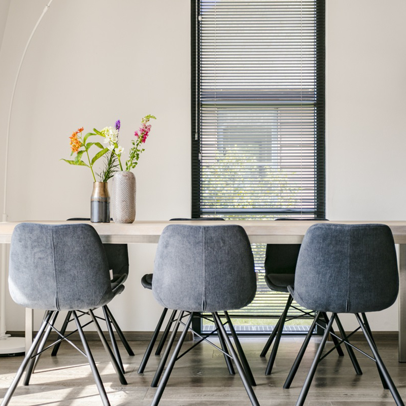 Moderne eettafel met grijze fauteuils in het vakantiehuis op het kleine park Weideduyn bij zee