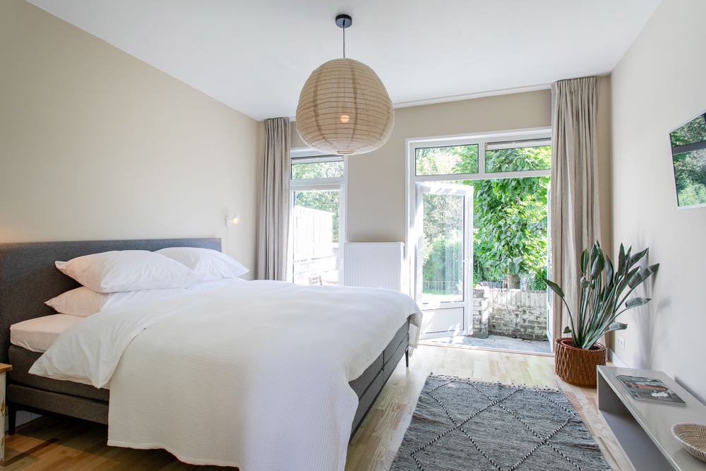 B&B kamer met groot bed, openslaande deuren en lichte tinten