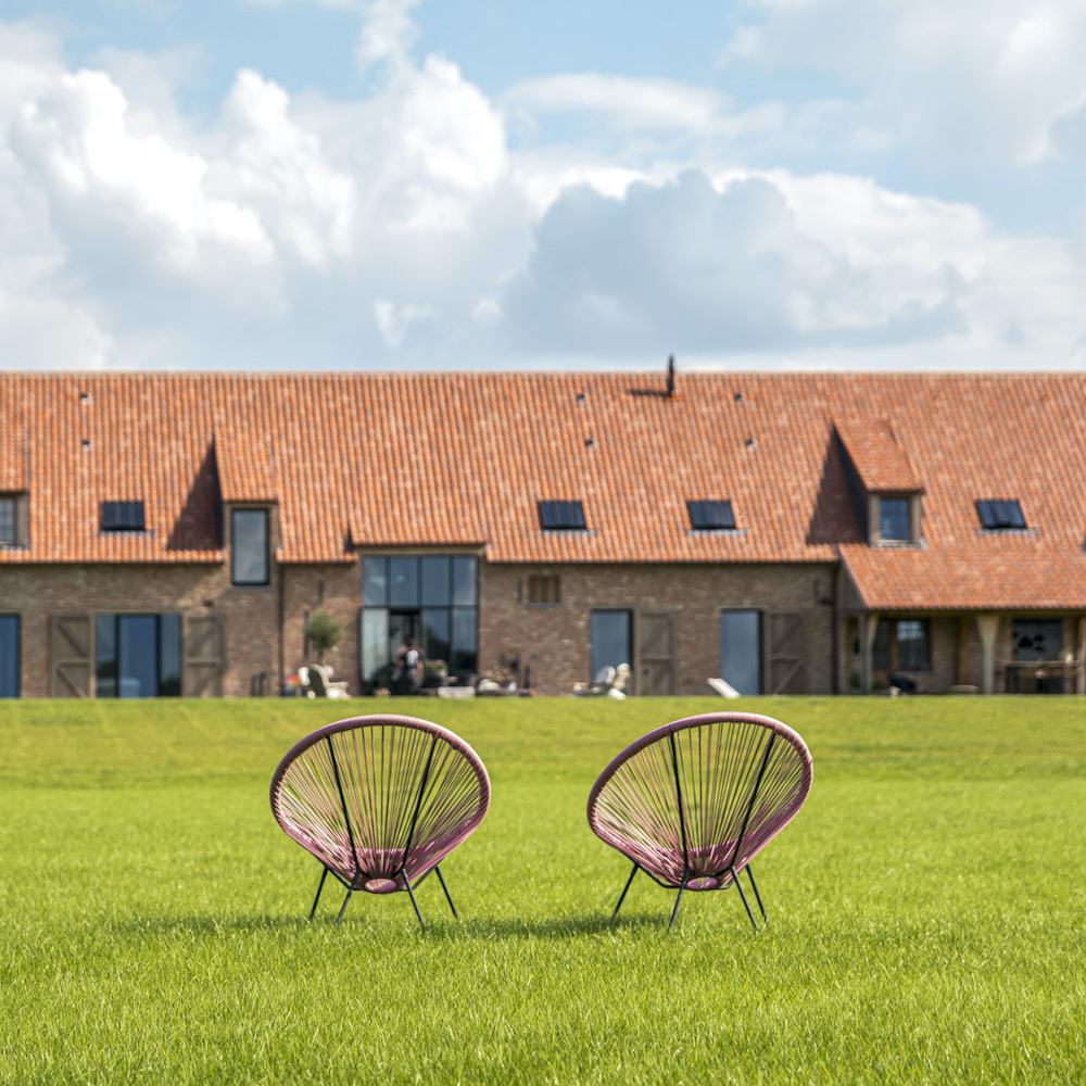 Stoelen im het gras met op de achtergrond de B&B