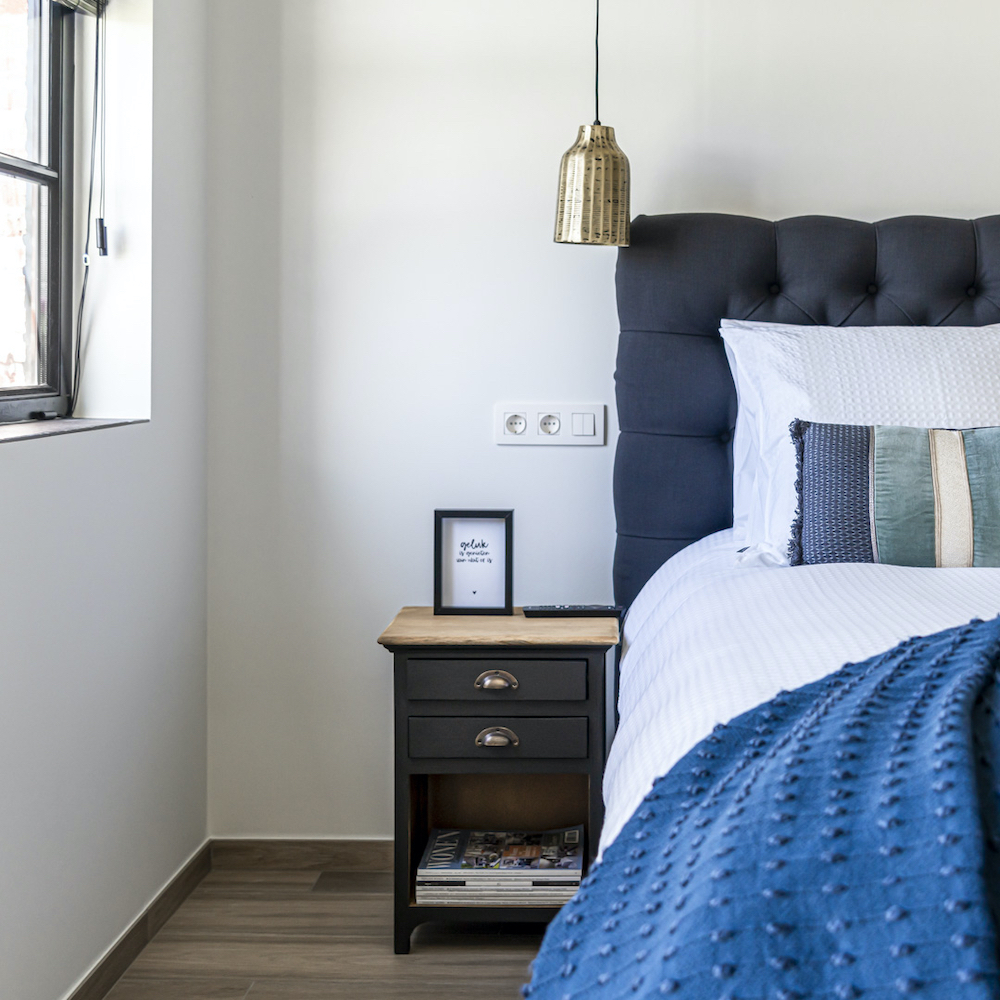 Bedhoofd en blauwtinten in de kussens en sprei