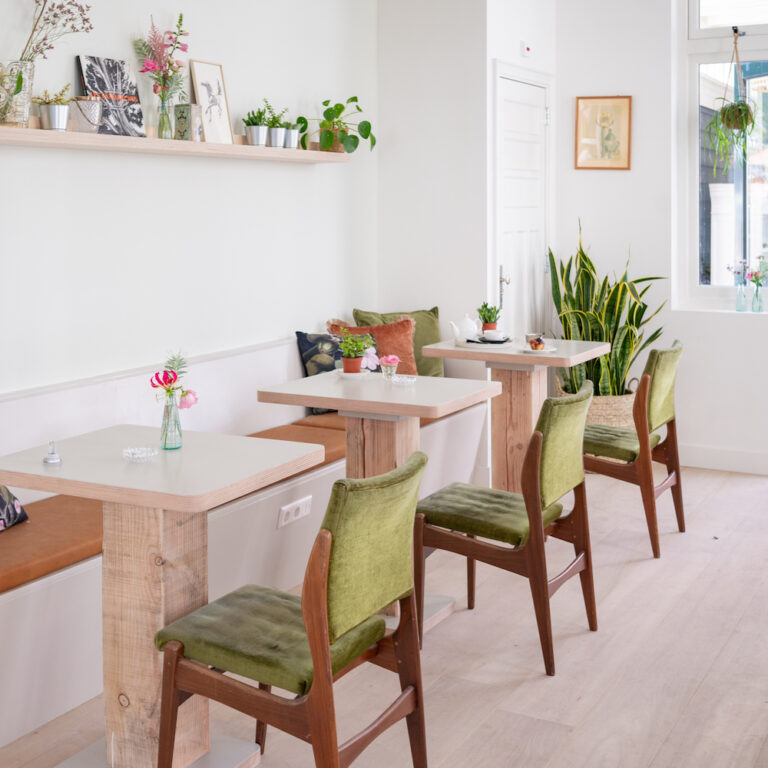Rijtje tafels met groen fluwelen stoelen in boutique hotel de Stadsherberg