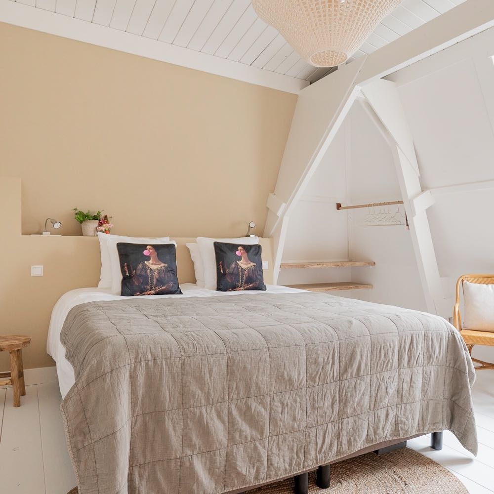 Hotelkamer met groot bed en kussens met een grootmeester erop