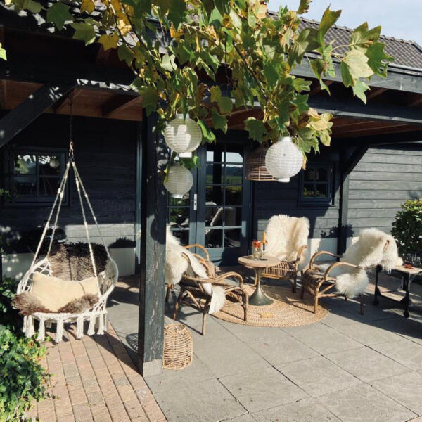 Overkapt terras met rotan stoelen met bontjes