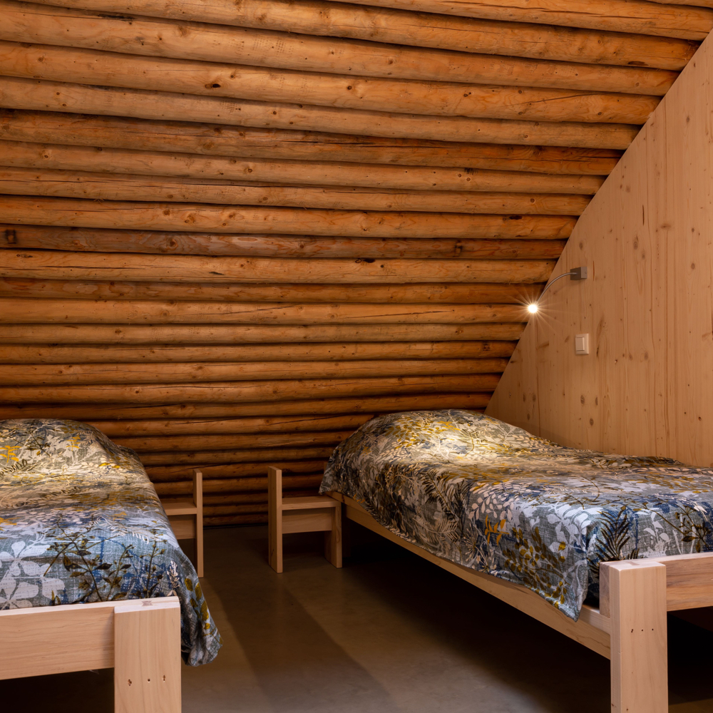 Slaapkamer met twee losse bedden onder een balkenpalfond