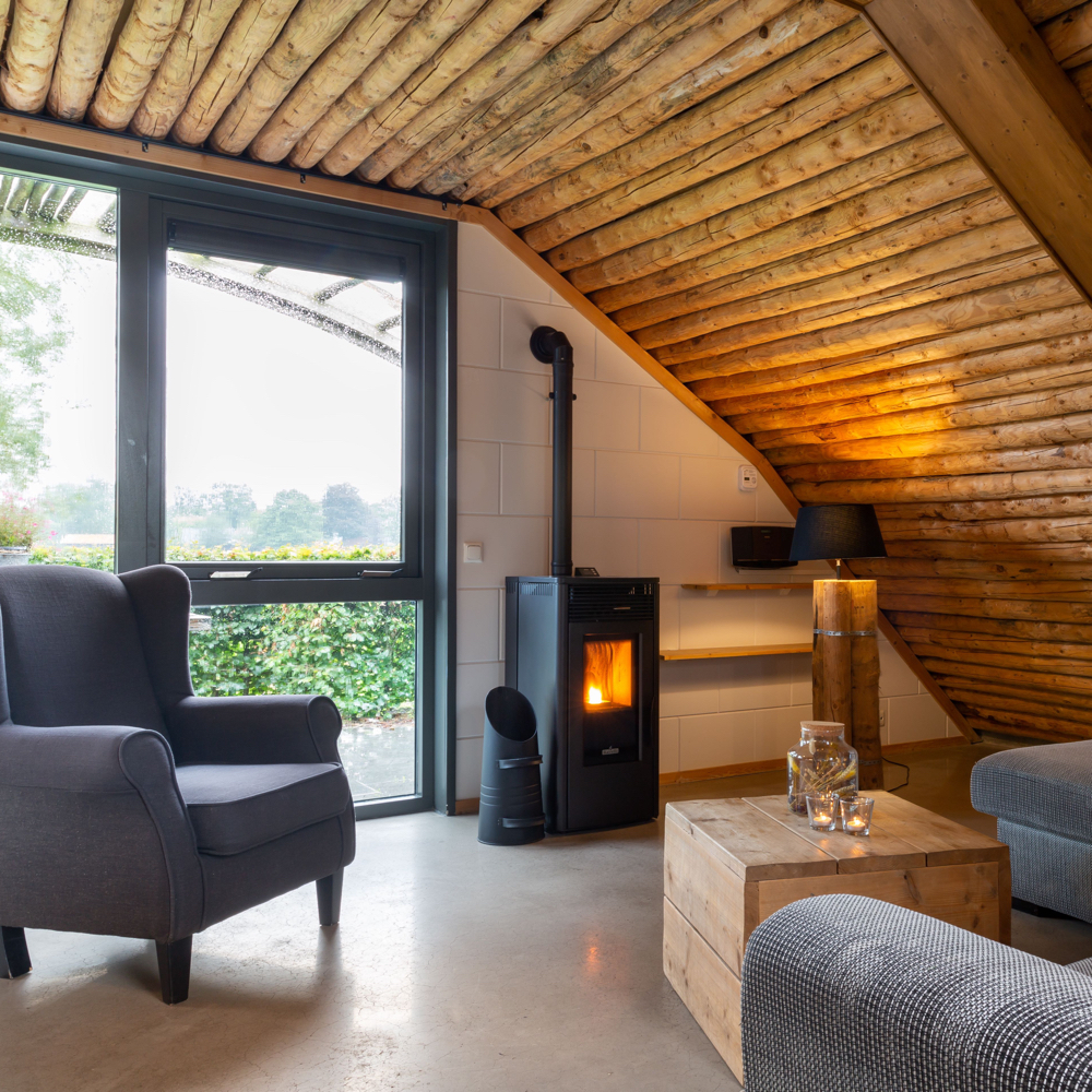 Zithoek met grijze fauteuil bij brandende haard