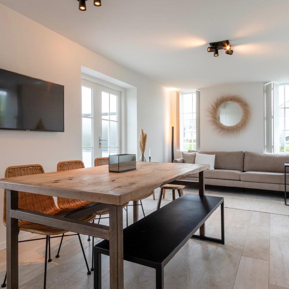 Eettafel met een bankje en drie stoelen in een vakantiehuis in Zeeland.