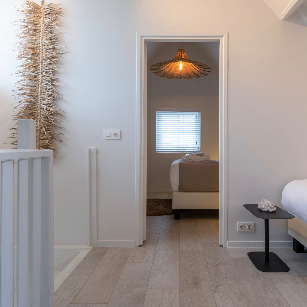 Slaapkamer met tweepersoonsbed en een extra bed op de overloop in het vakantiehuis in Zeeland