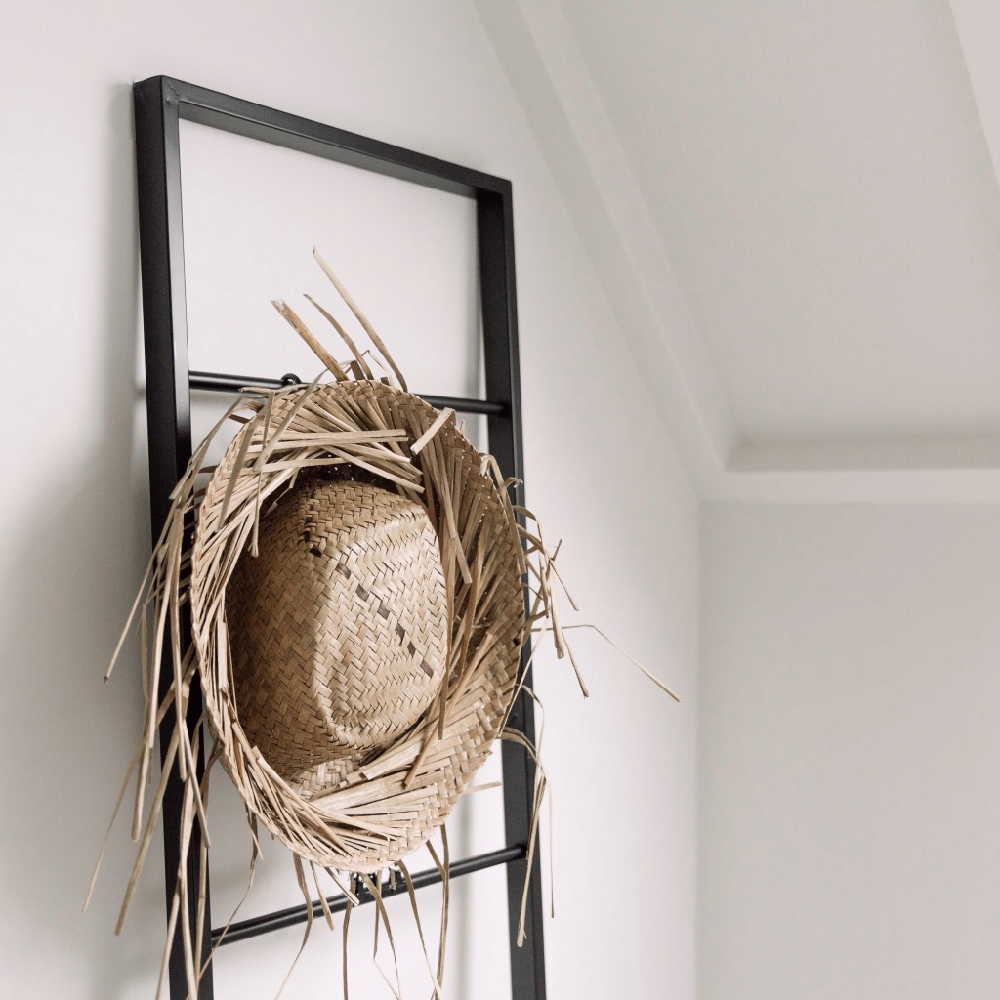 Strohoed hangend aan een rek in een vakantiehuis aan de duinopgang in Zeeland