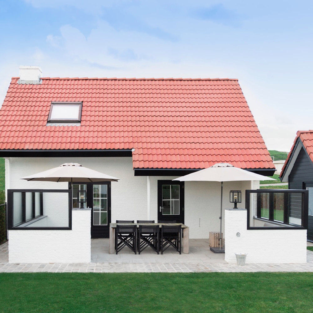 Terras met windschermen en een omheinde tuin bij het vakantiehuis aan de duinopgang in Zeeland
