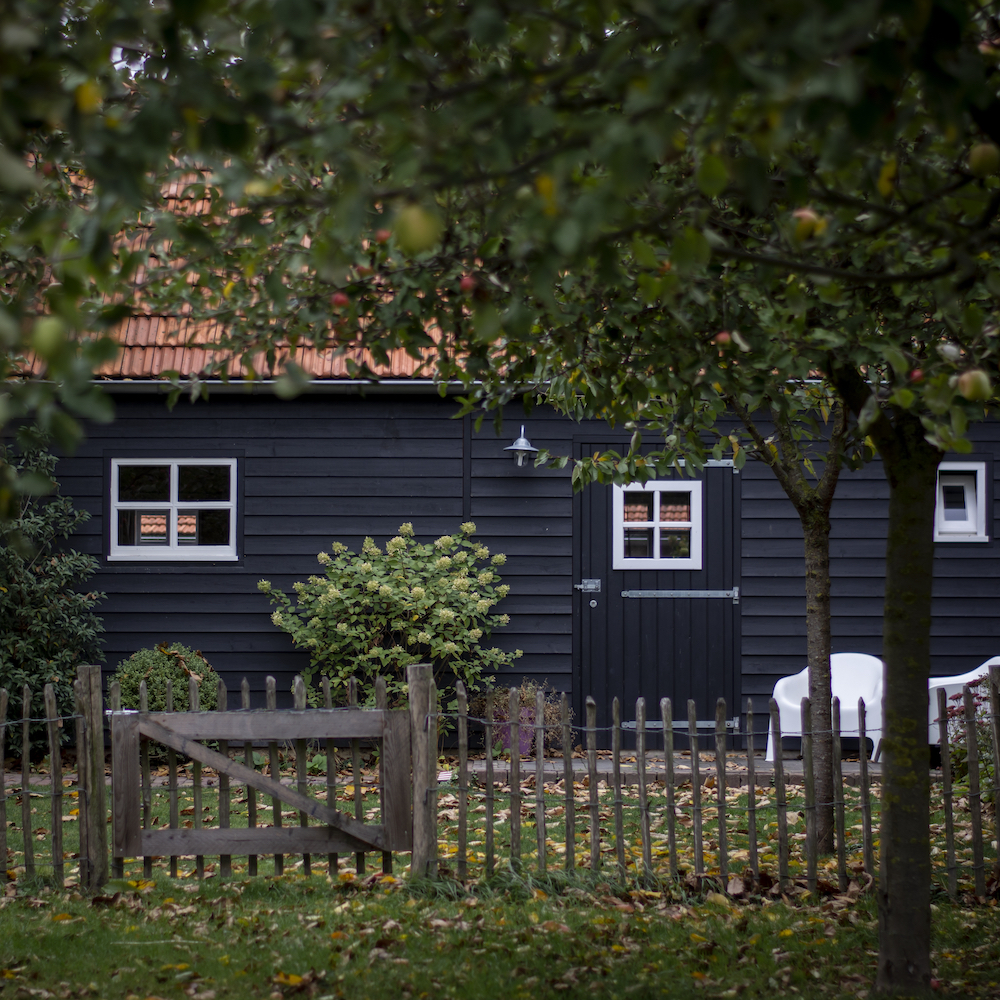 Zwart houten huisje voor twee personen met twee witte stoeltjes