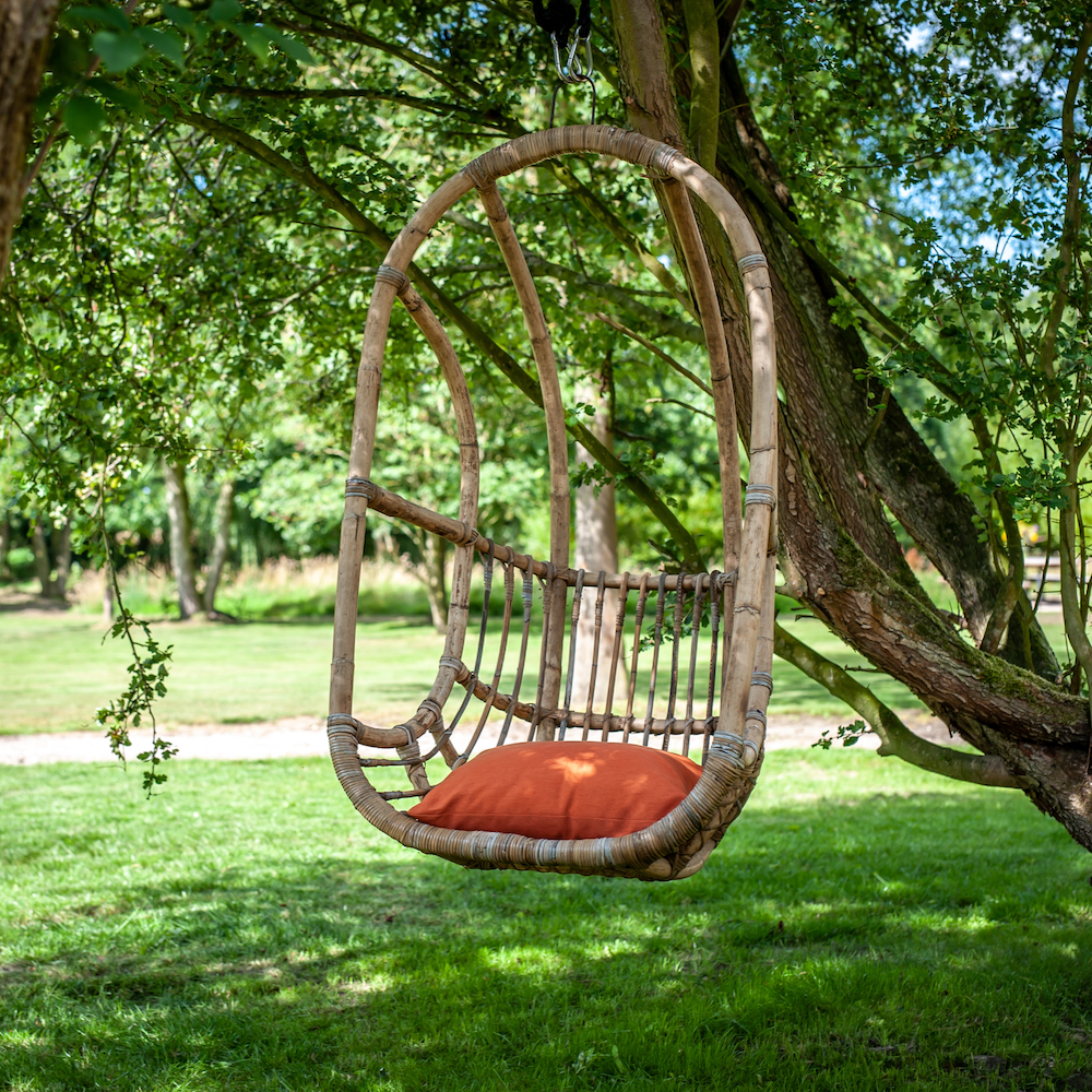 Hangstoel met rood kussentje in de tuin van de Steurshoeve