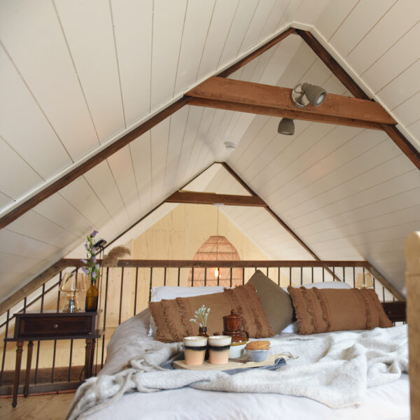 Slaapkamer met ouderwets balkenplafond in een vakantiehuis in Friesland