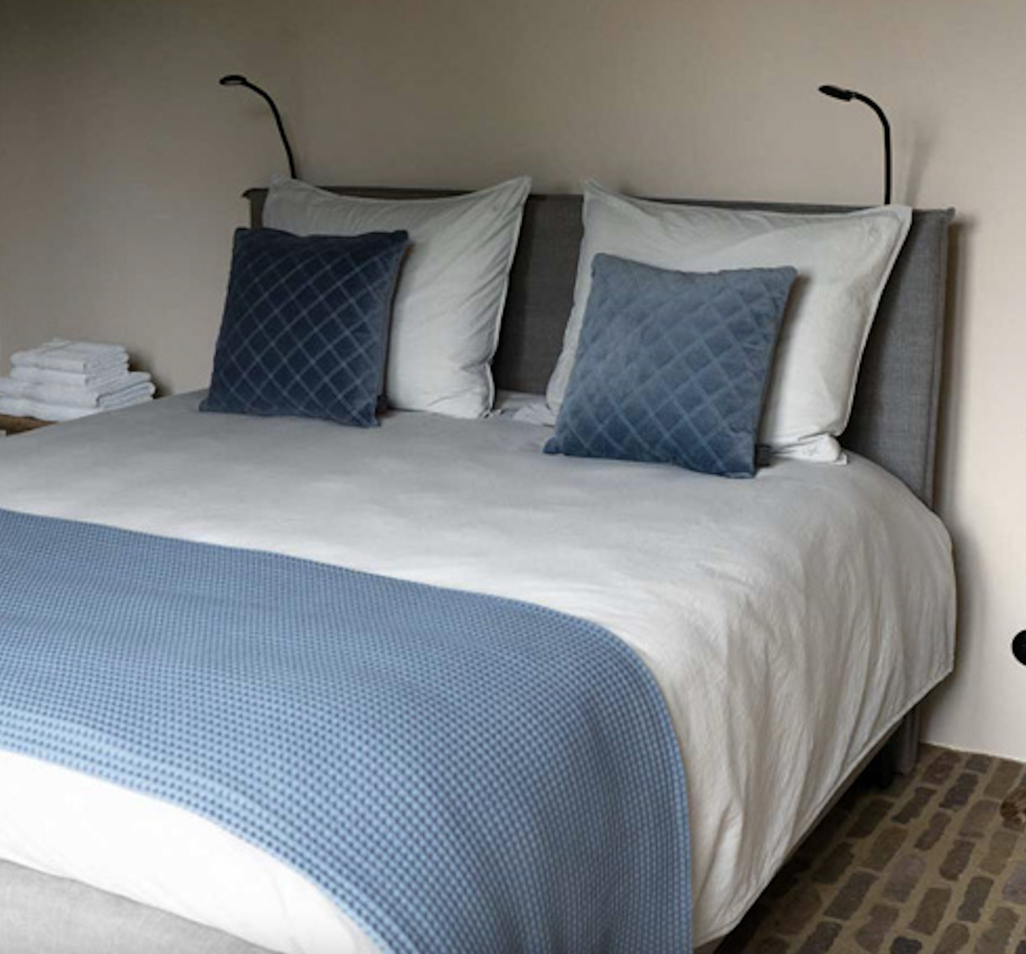 Opgemaakt bed met blauwe sprei en kussens