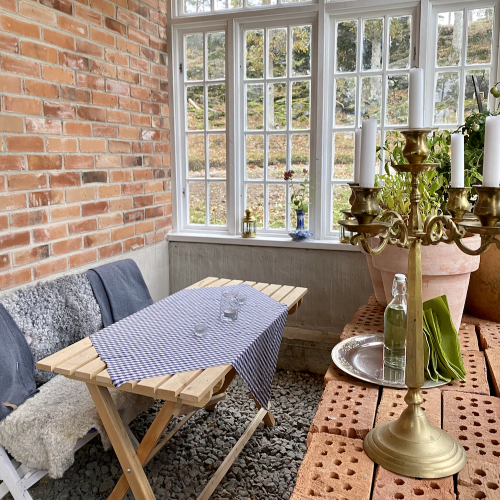 Orangerie met een tafel met blauw kleedje en een kandelaar.