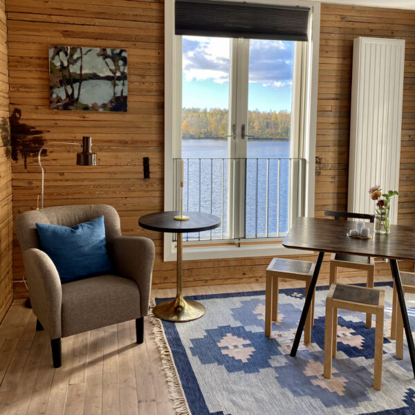 Zithoek met beige fauteuil en uitzicht over het meer.
