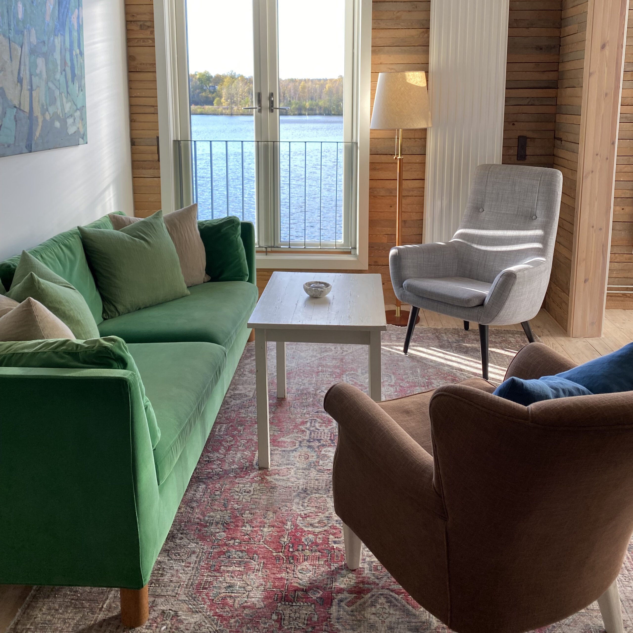 Zithoek met groene bank en uitzicht op het meer.