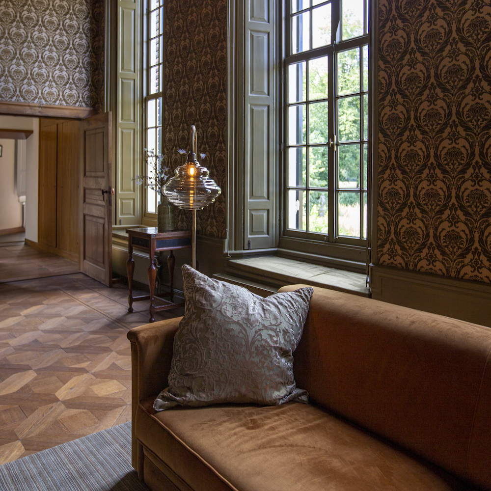 Bank met schemerlamp in een van de suites op het kasteel