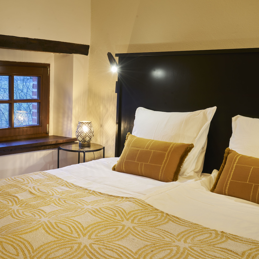 Slaapkamer met tweepersoons bed met warme geeltinten