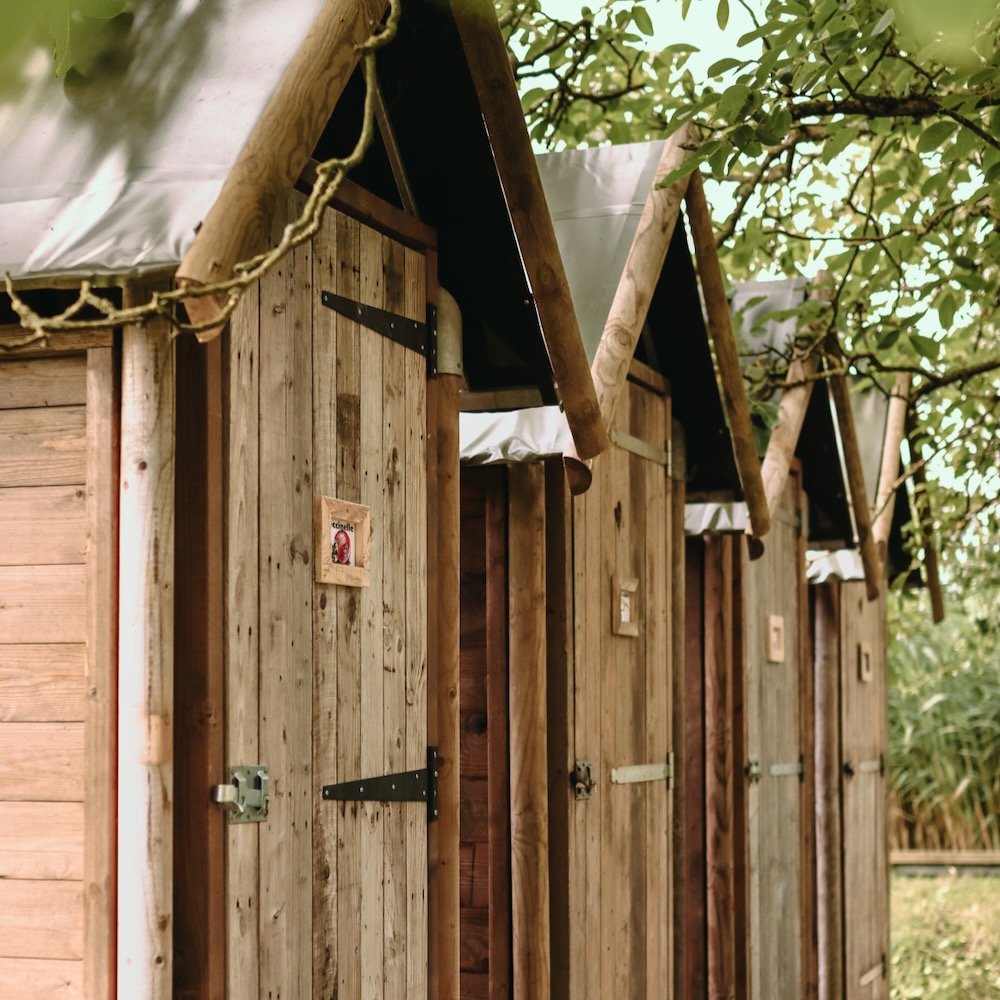 Vier houten cabins op een rij met een douche erin