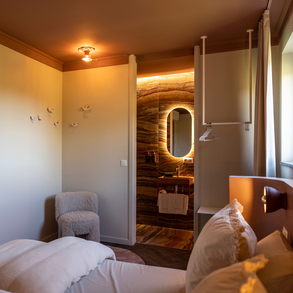 Slaapkamer met stoel en badkamer bij vakantiehuis in de Voerregio