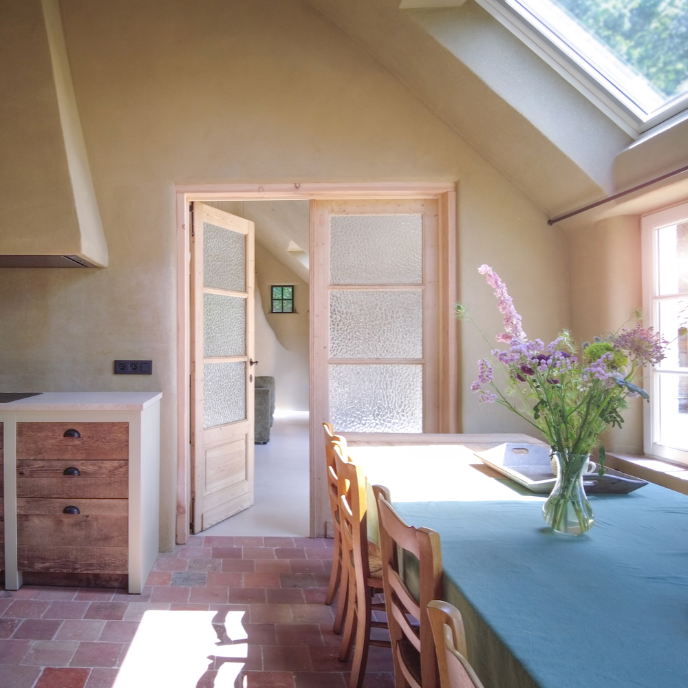 Eettafel met glazen deuren naar een zitruimte in vakantiehuis in Vlaanderen