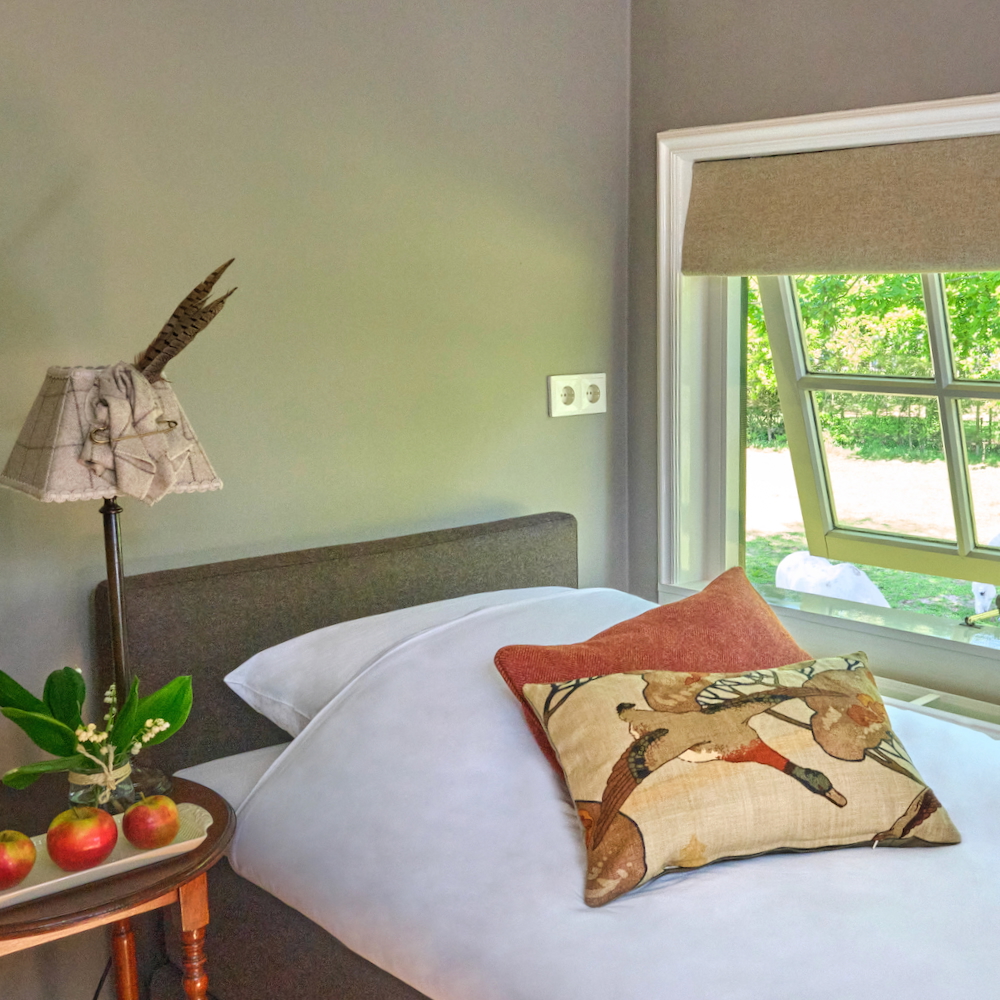 Bed in slaapkamer met natuurlijk licht en nachtkastje in Leersum
