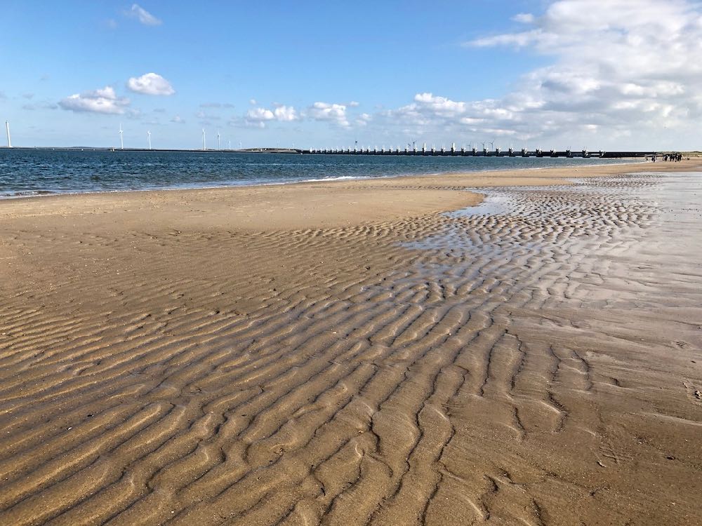 Sonnenstrand mit den Deltawerken in der Ferne