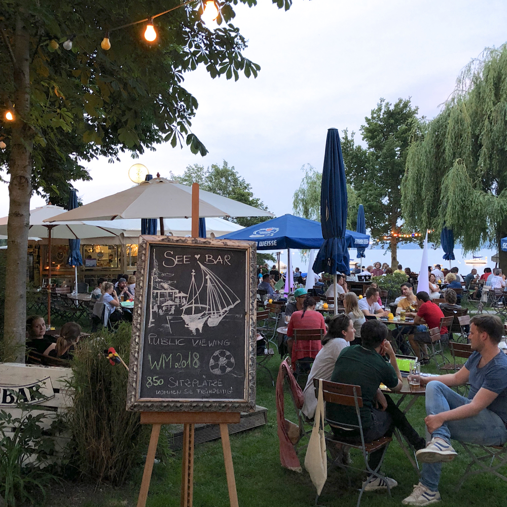 Eine volle Terrasse am Wasser See Bar