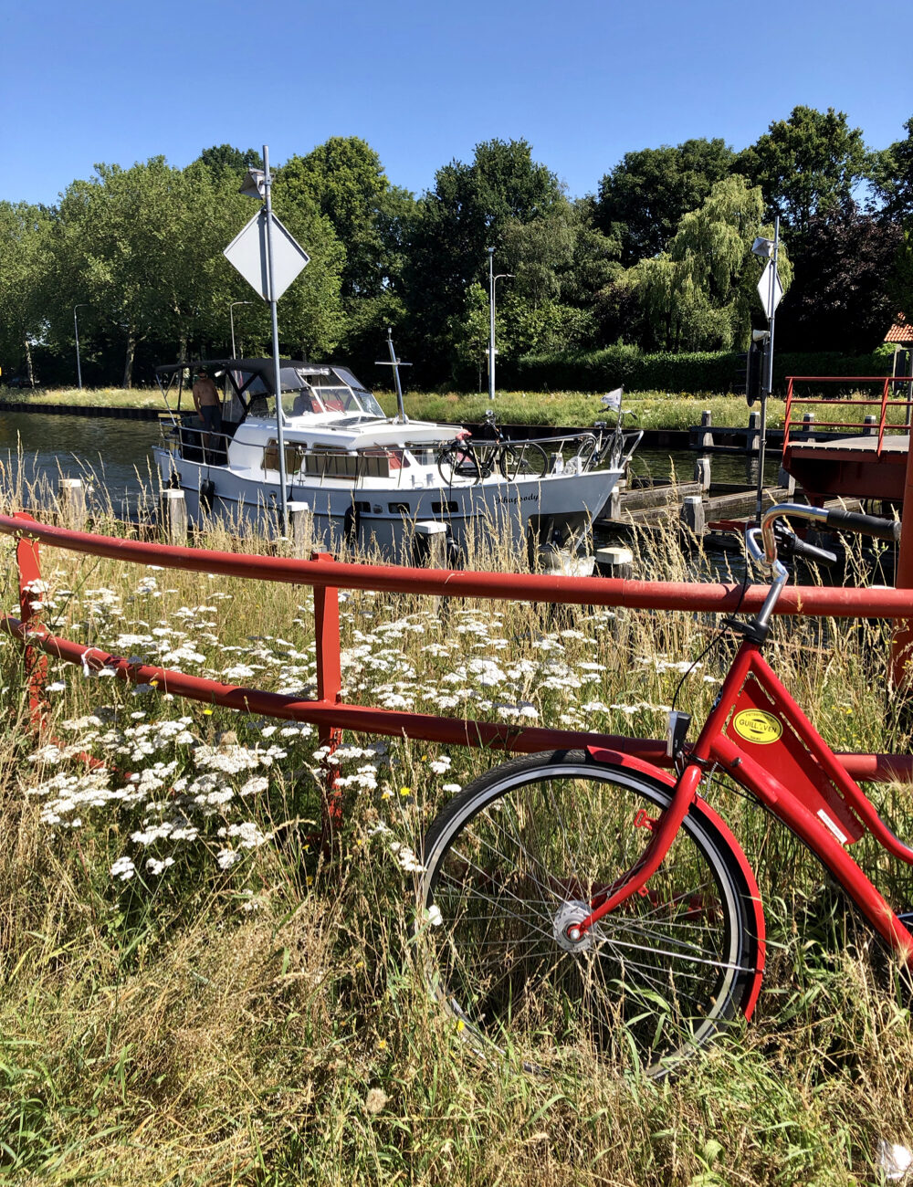 Rotes Fahrrad entlang des Kanals mit Vergnügungsjacht