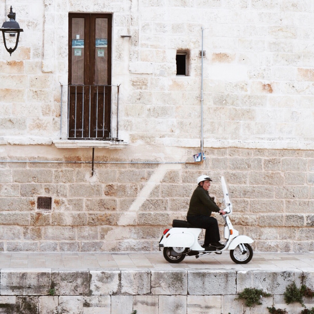Mann auf weißer Vespa, in den Straßen von Polignano a Mare