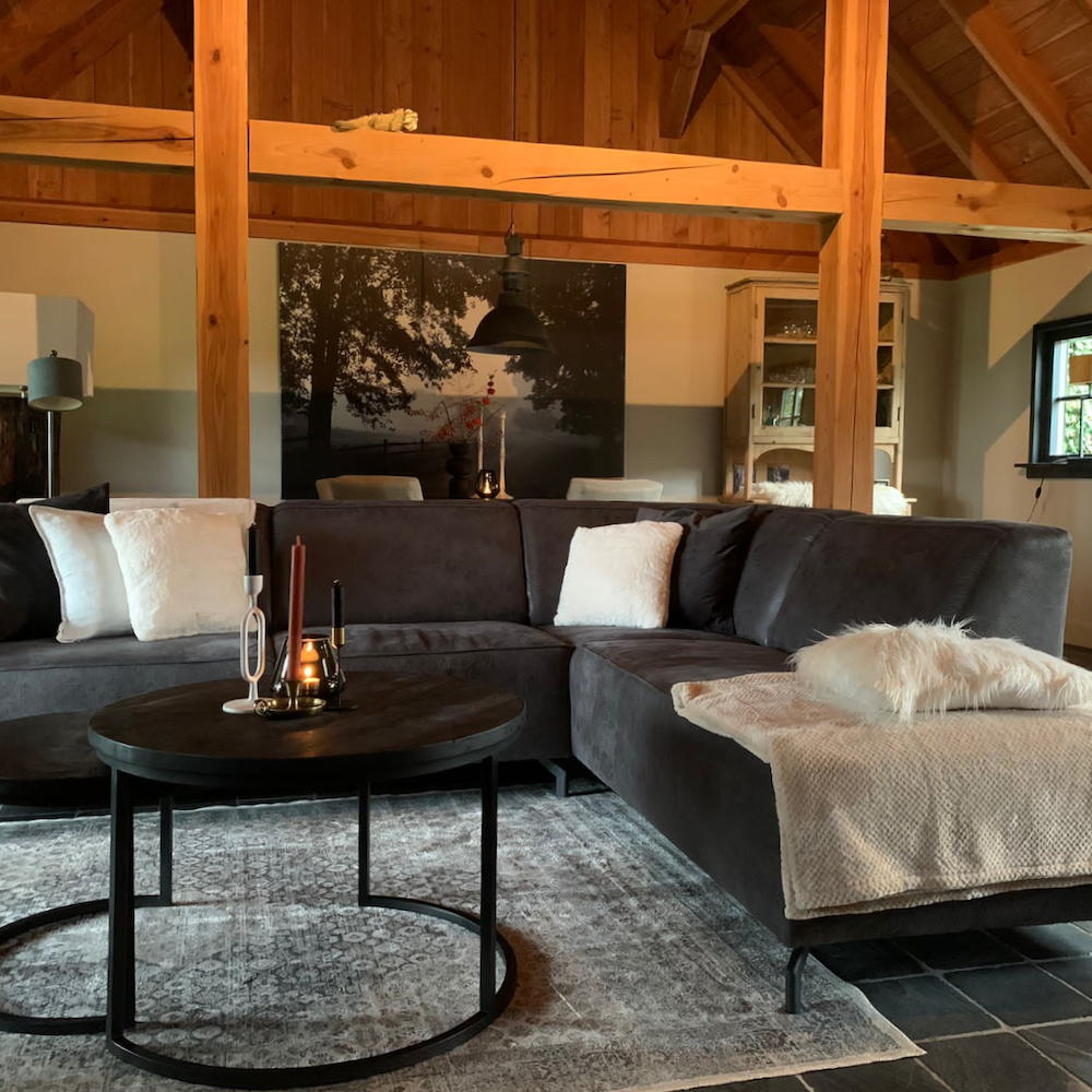 Sitzecke mit grauem Ecksofa und warmen Plaids und Kissen