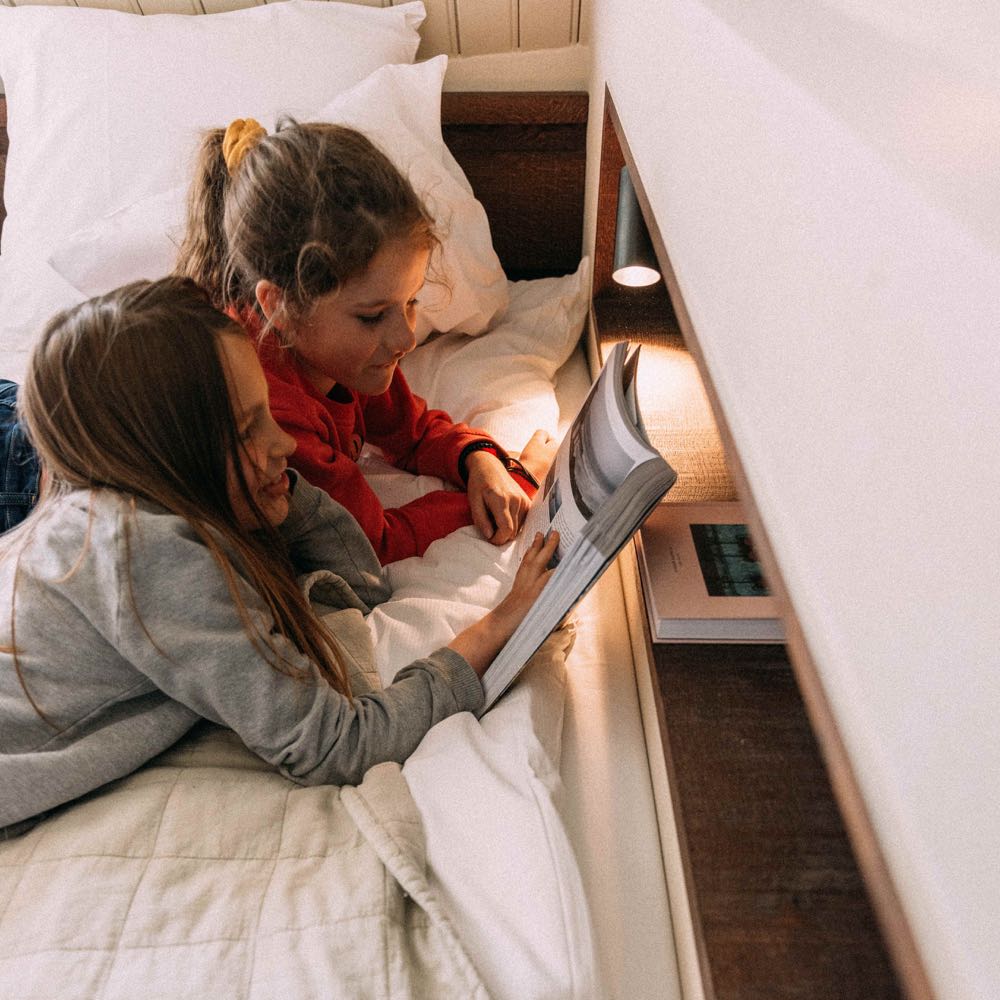 Kinder lesen ein Buch im Bett