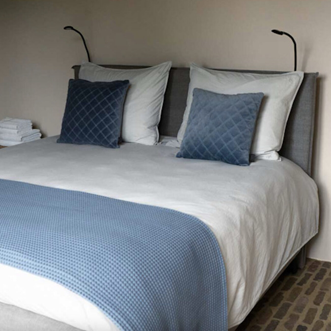 Gemachtes Bett mit blauer Tagesdecke und Kissen