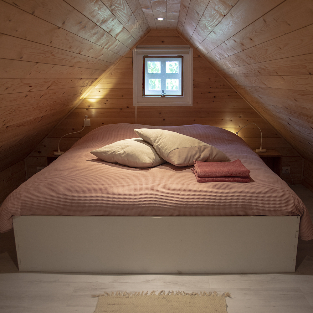 Doppelbett auf dem Dachboden der gemütlichen Hütte