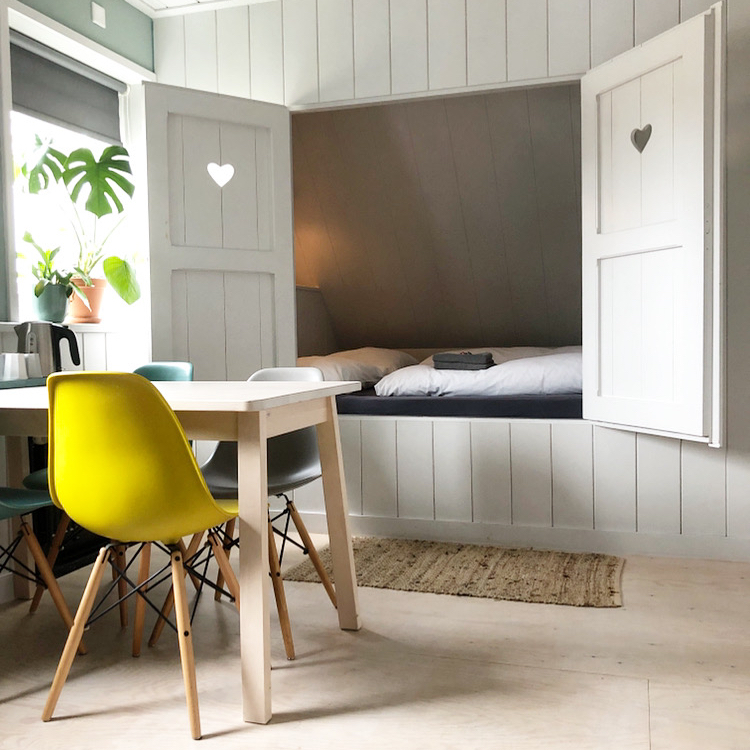 Bettgestell mit Sitzecke mit farbigen Stühlen