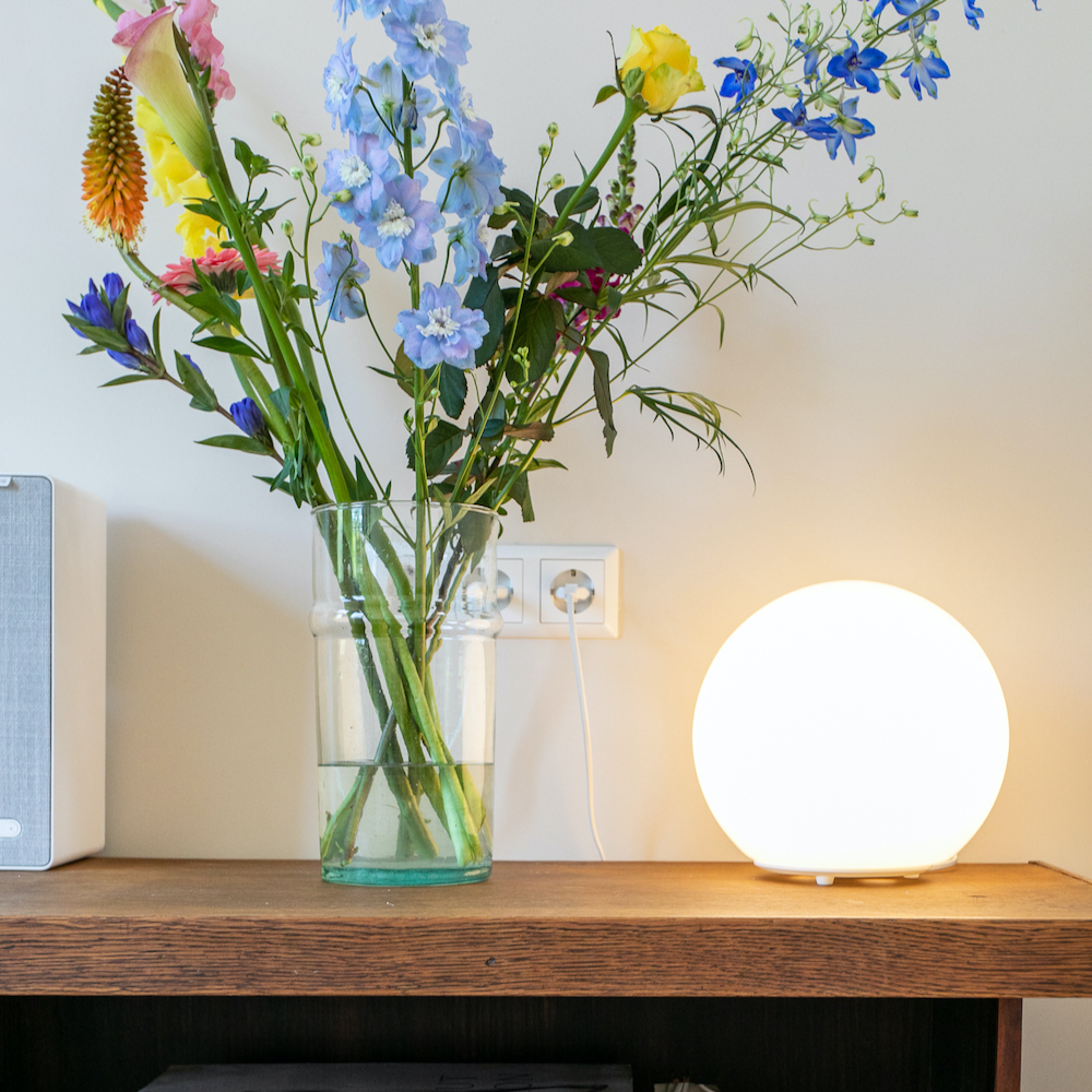 Blumen in der Vase neben einer Kugellampe