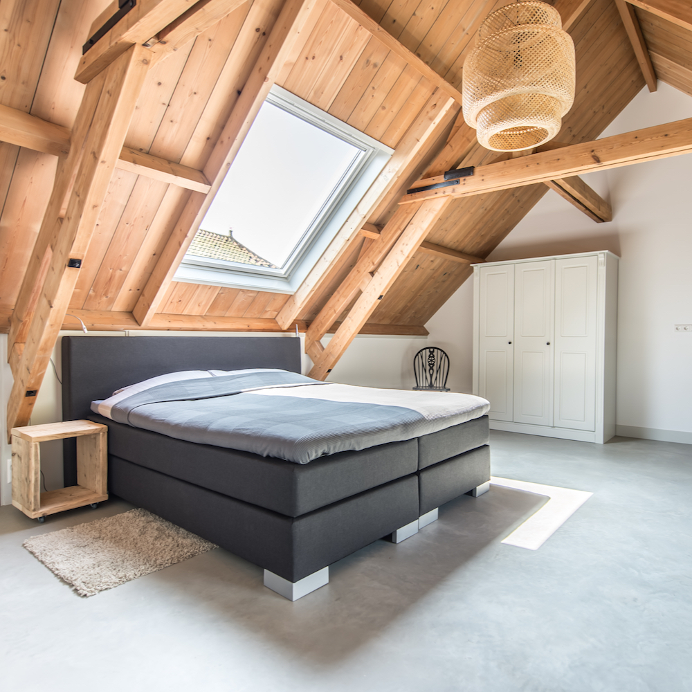 Schlafzimmer unter dem Dachstuhl mit großem Oberlicht über dem Bett