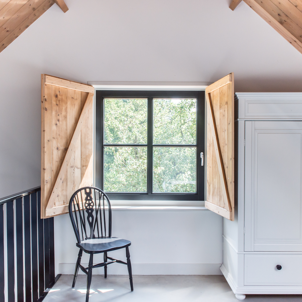 Fenster mit hölzernen Fensterläden auf dem Treppenabsatz des Ferienhauses