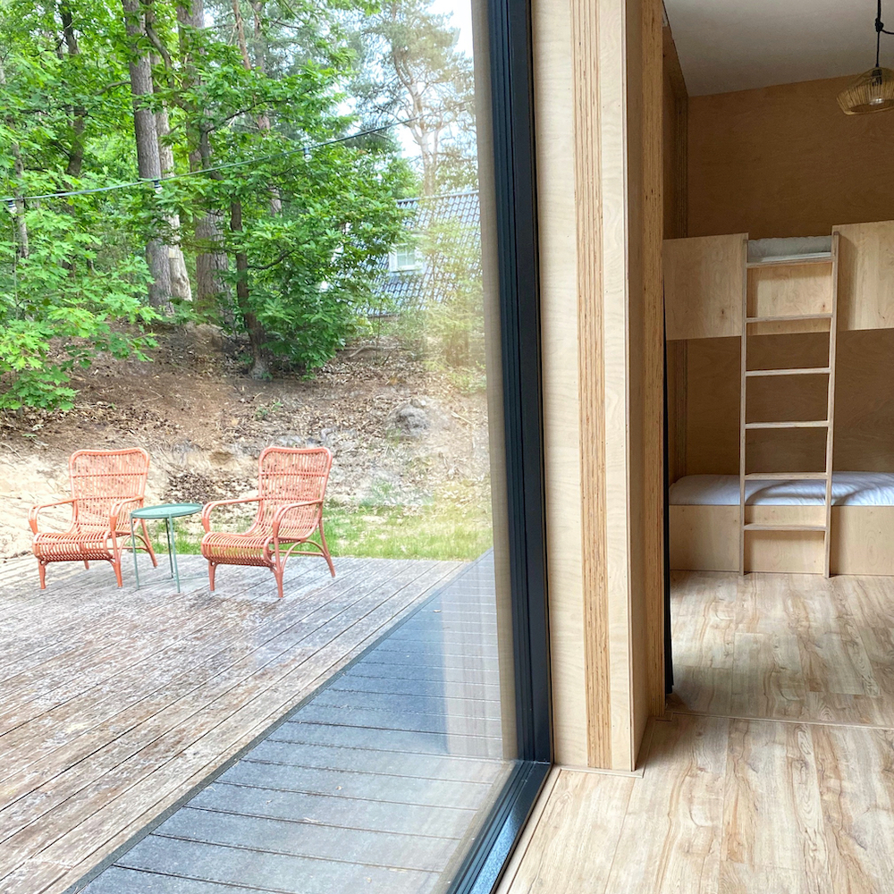 Ferienhaus mit großen Fenstern mit Terrasse außen und Schlafzimmer innen