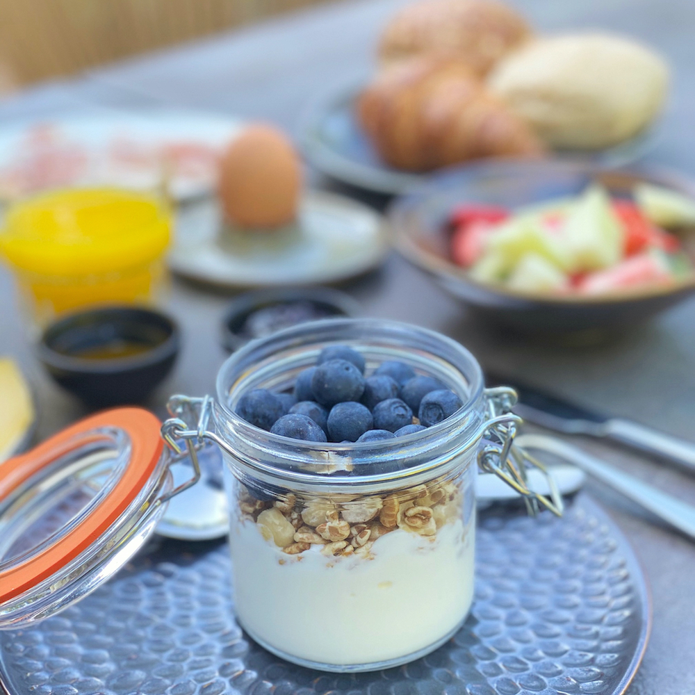 Frühstück mit Joghurt, Blaubeeren, Müsli, frischem Obst, Ei und Saft