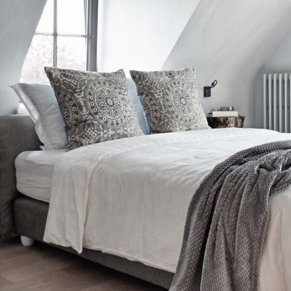 Helles, luxuriöses Bed & Breakfast-Zimmer mit grauer Tagesdecke und weicher Bettwäsche