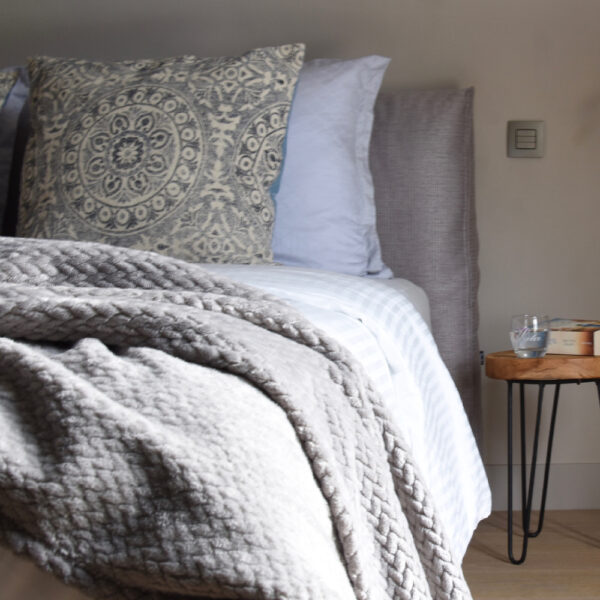 Graue Tagesdecke mit Luxuskissen auf dem Bett im B&B-Zimmer