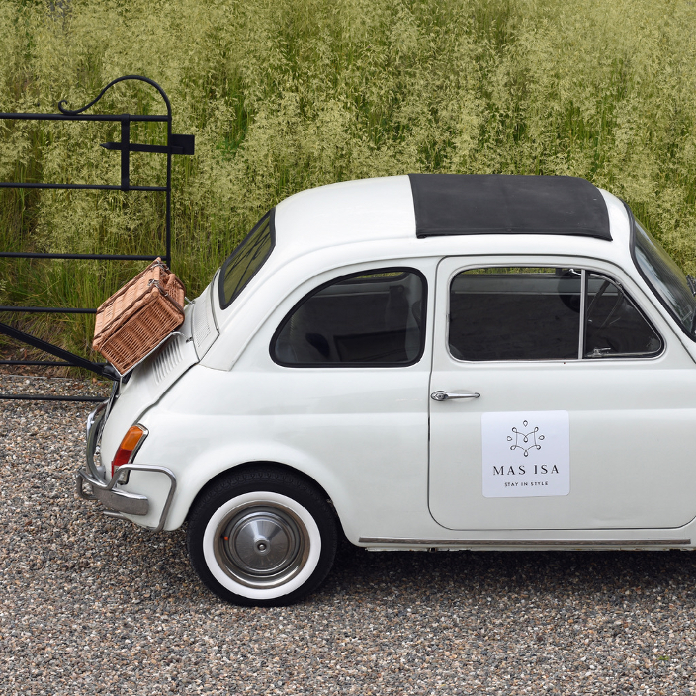 Fiat 500 in Weiß, mit einem Weidenkoffer auf der Rückbank